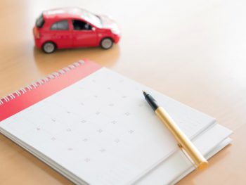 calendar with a gold pen sitting on a desk with a red toy car