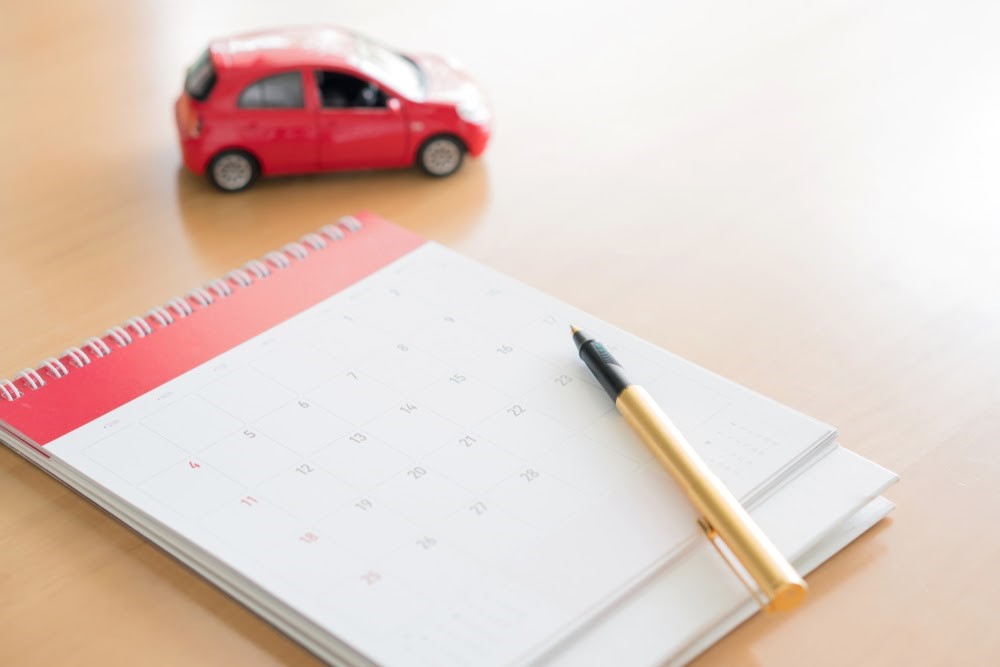 calendar with a gold pen sitting on a desk with a red toy car